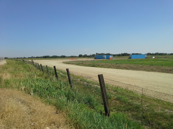 Protesters observe the capped well head and pad at the Smoke Ranch site south of Highway 52, the first directionally drilled natural gas well in the state, located in a floodplain full of standing water, wetlands, irrigation canals, riparian areas, and a wildlife refuge, between the Payette River and Big Willow Creek, only a few miles upstream from the City of Fruitland municipal water intake and the Payette/Snake River confluence.