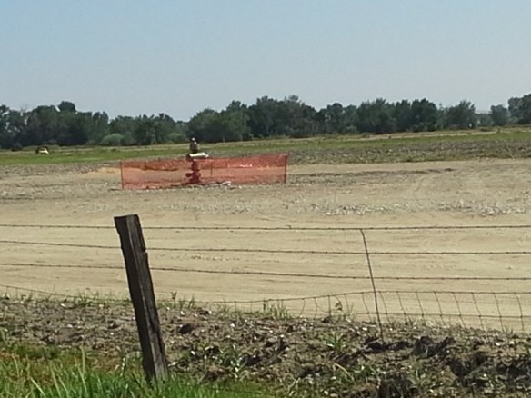 Protesters observe the capped well head and pad at the Smoke Ranch site south of Highway 52, the first directionally drilled natural gas well in the state, located in a floodplain full of standing water, wetlands, irrigation canals, riparian areas, and a wildlife refuge, between the Payette River and Big Willow Creek, only a few miles upstream from the City of Fruitland municipal water intake and the Payette/Snake River confluence.