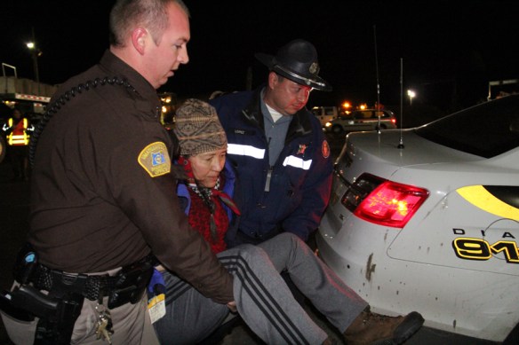 Law enforcement officers carry Cathy Sampson-Kruse to a patrol car, before placing her under arrest for disorderly conduct on Monday at the Port of Umatilla. Sampson-Kruse laid down in front of the megaload truck, in an attempt to prevent its departure. The megaload is currently stalled on Highway 395 south of Pendleton by weather (Hermiston Herald/Colin Murphey photo).